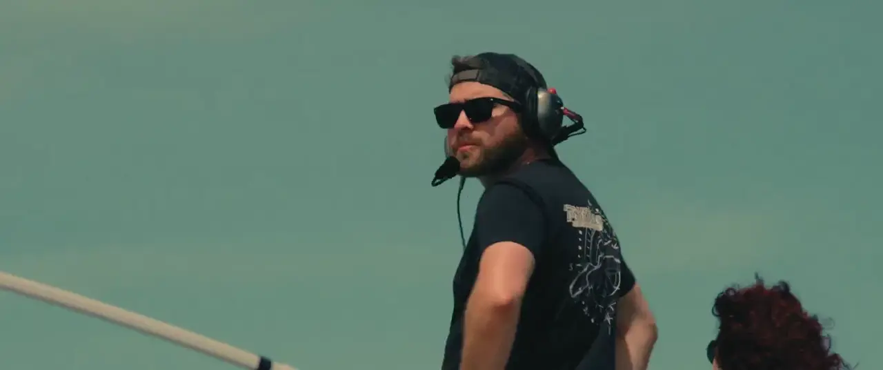 A crew member in sunglasses and headset watching the track