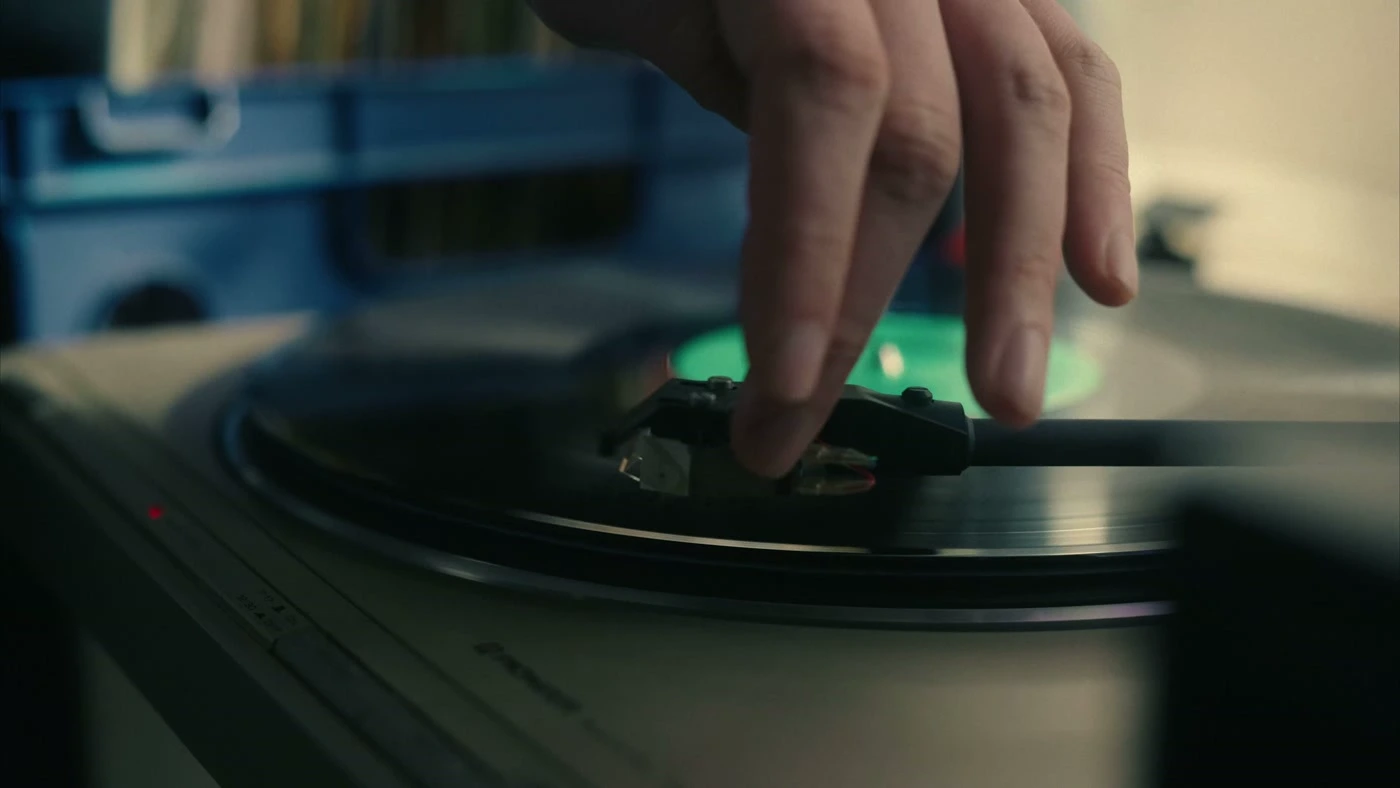 Close-up of a hand dropping a needle onto a spinning vinyl record